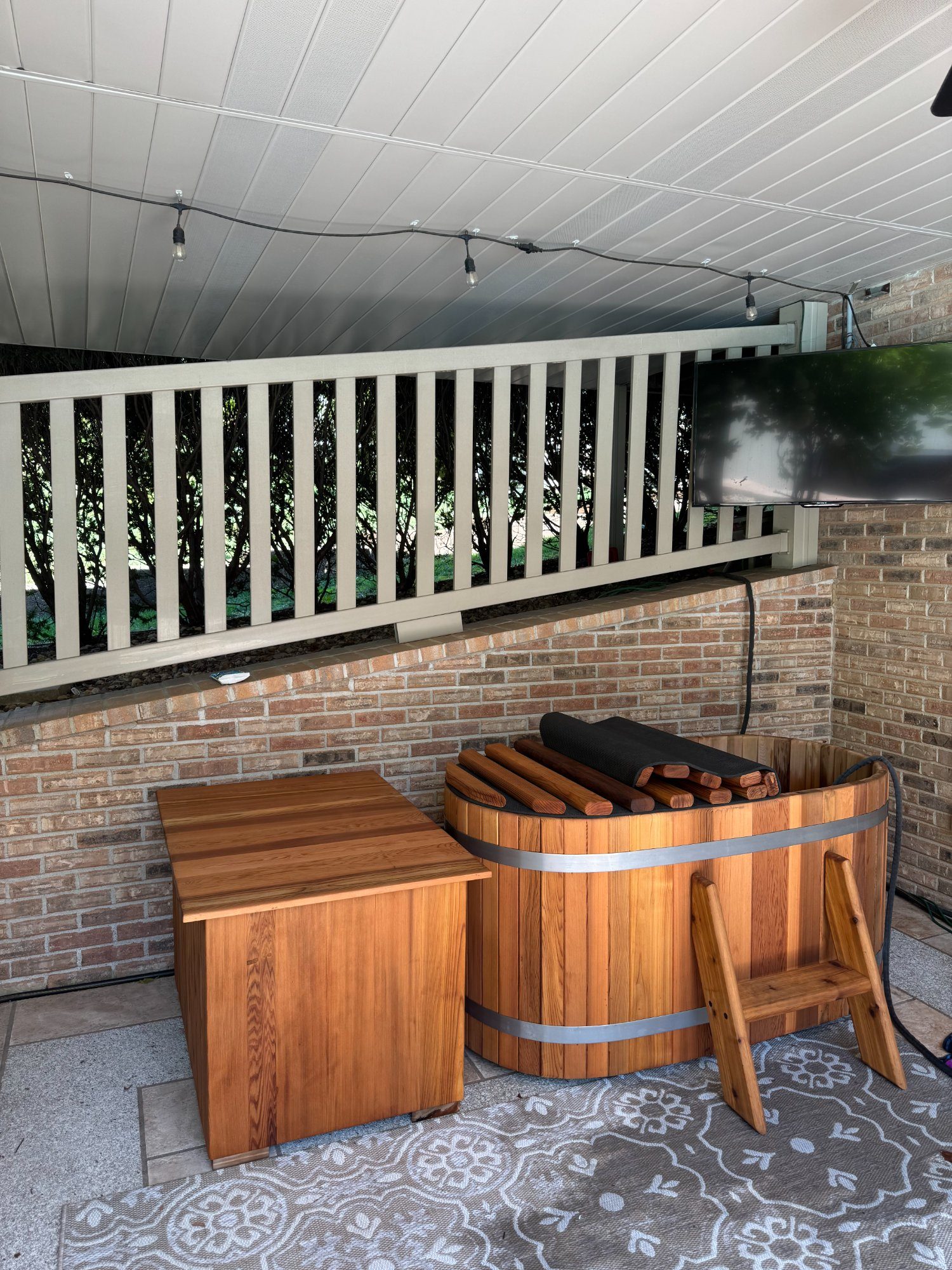 cedar cold plunge installed on covered deck with string lights
