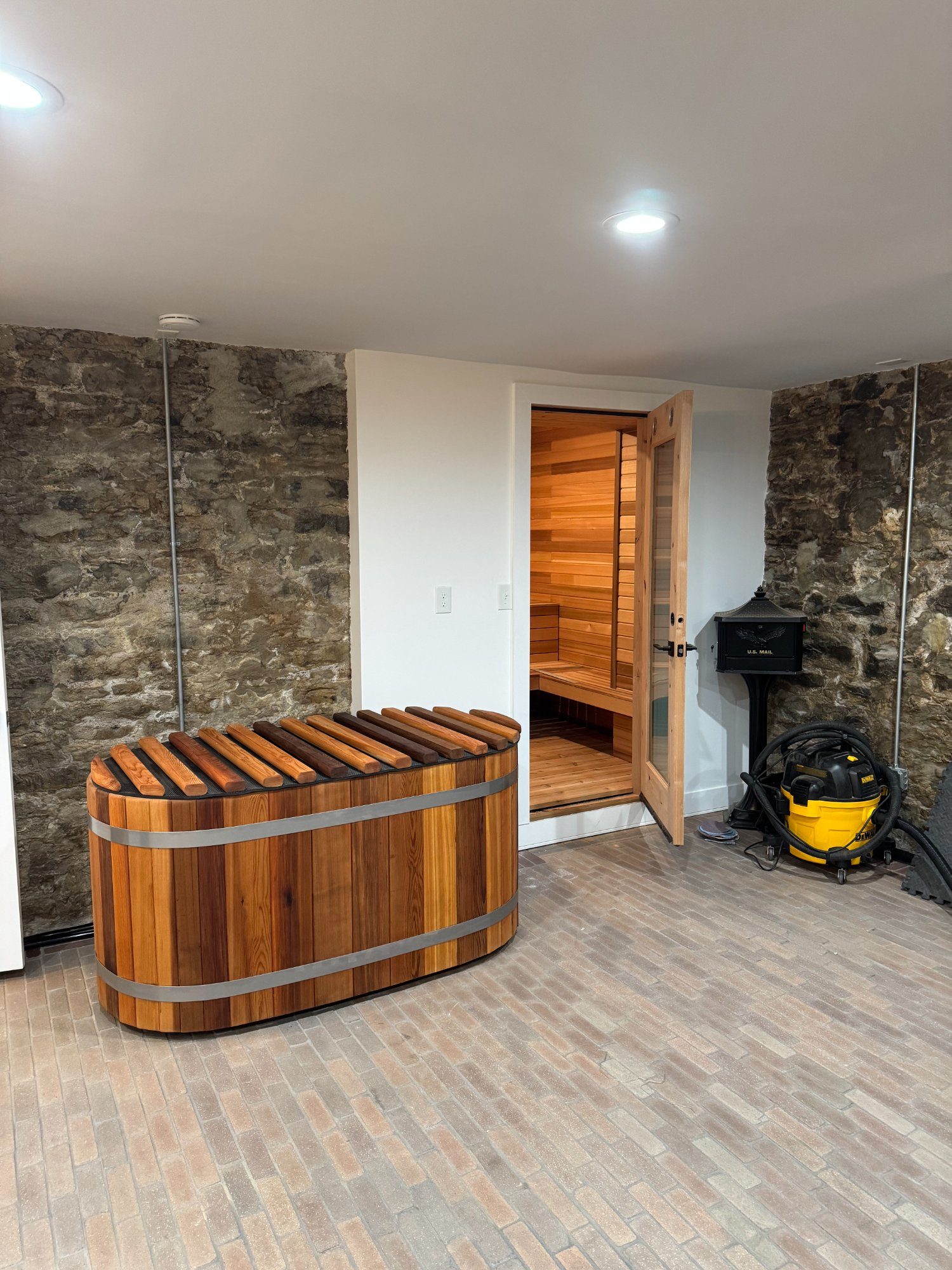 cedar cold plunge and sauna side by side in stone-walled basement