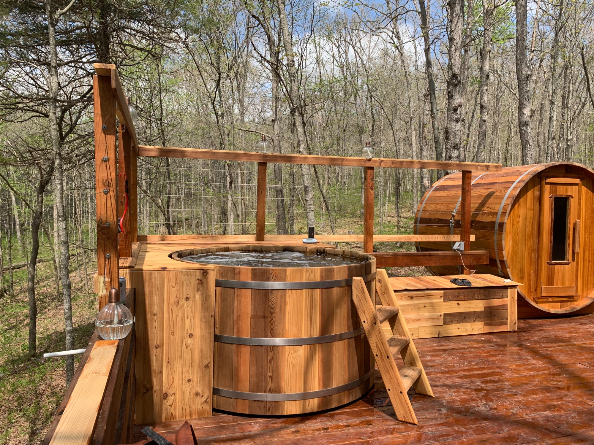 cedar hot tub and matching barrel sauna side by side on a woodland deck