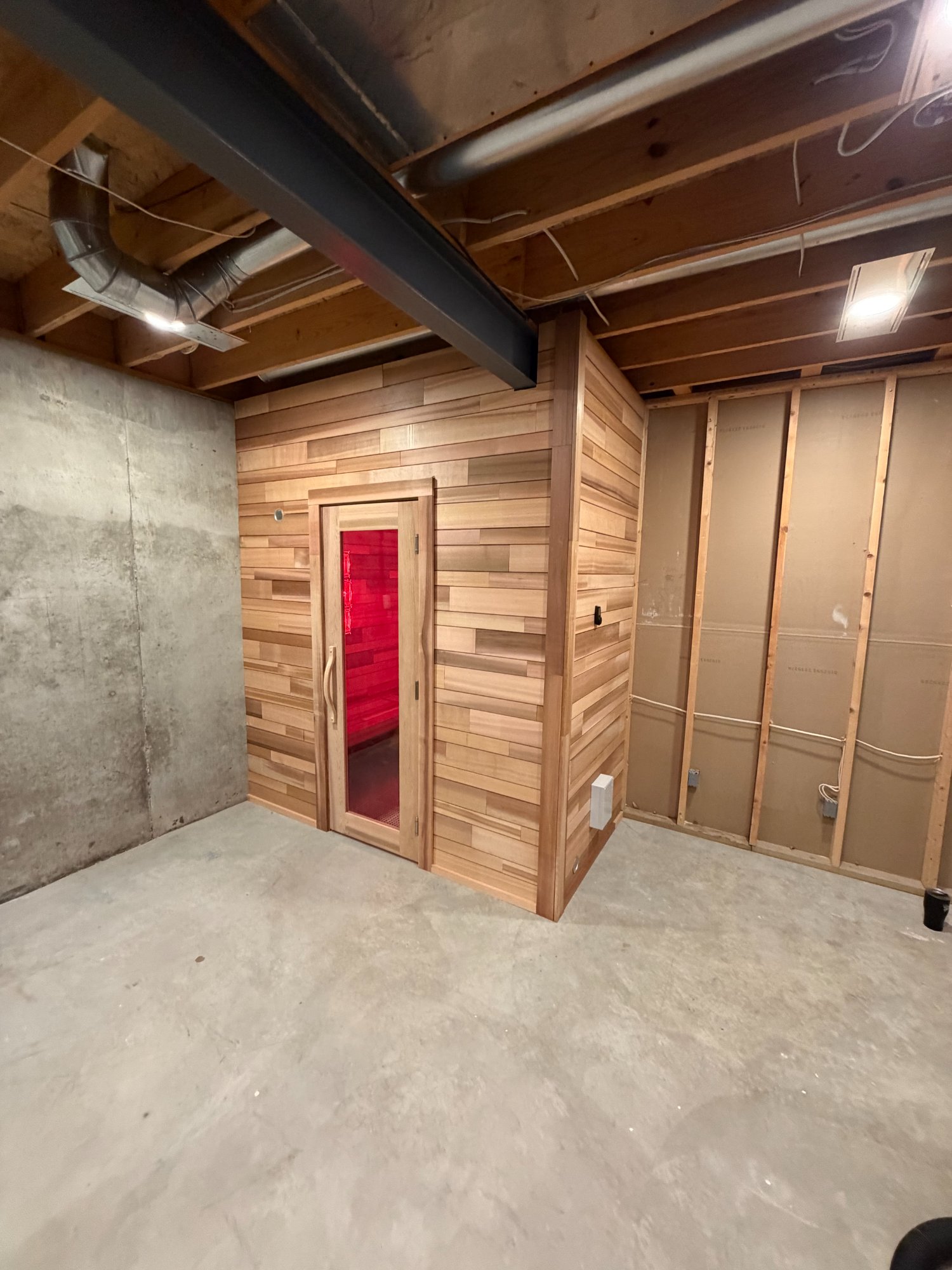 cedar sauna with red light therapy glow installed in an unfinished basement in St. Louis