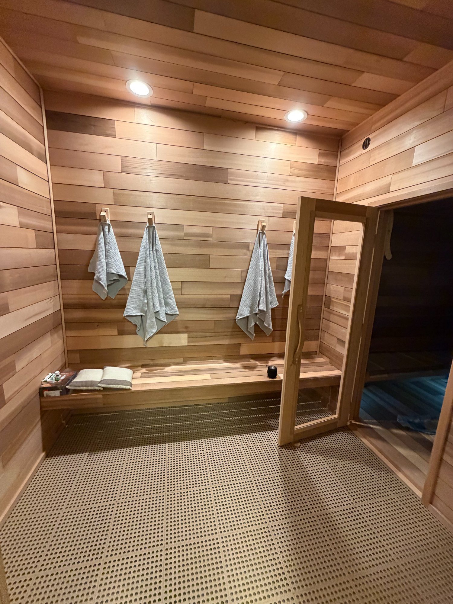 cedar sauna interior with towel hooks, bench, and recessed lighting in St. Louis home
