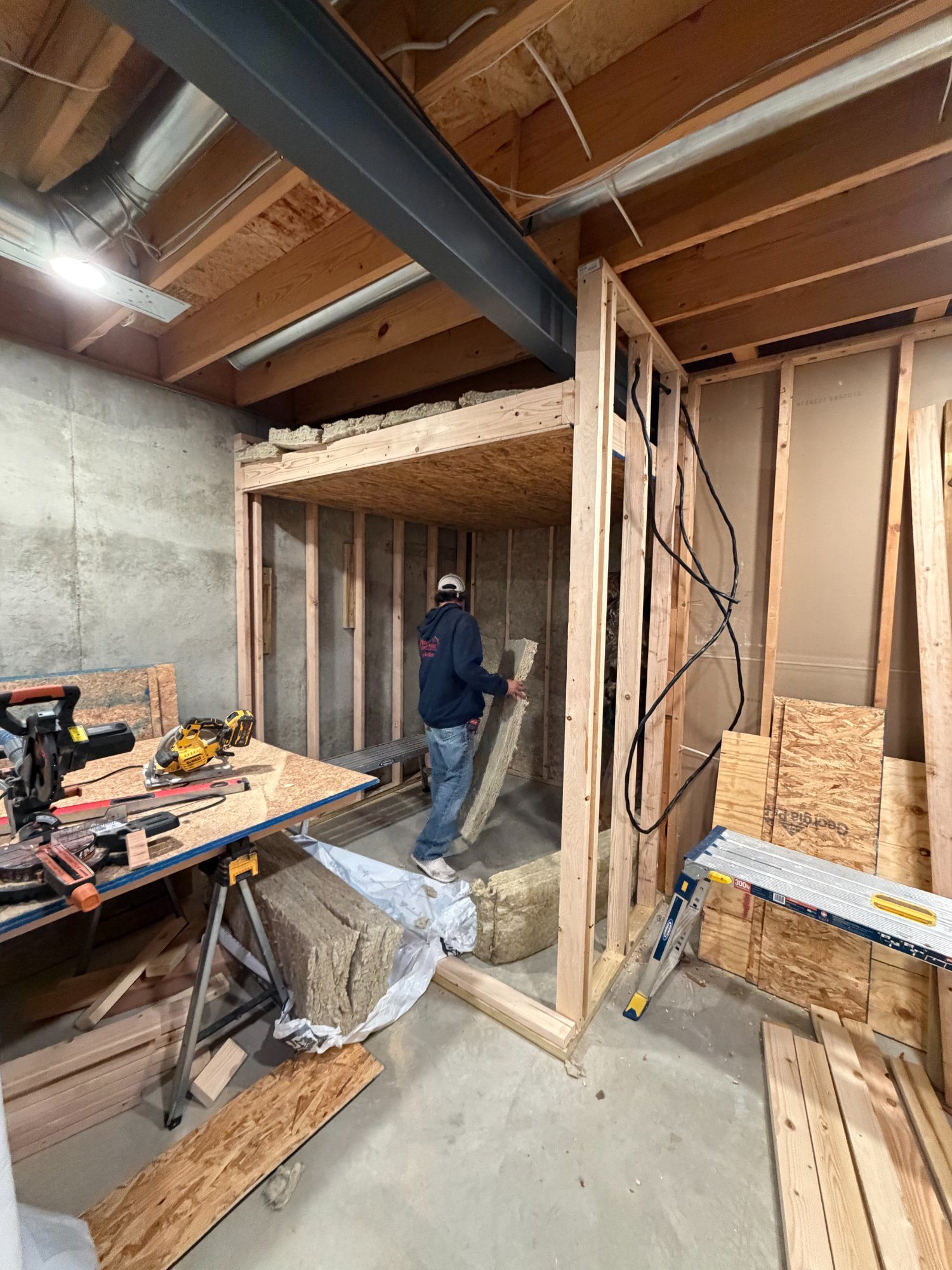 Craftsman installing insulation inside framed sauna structure in basement